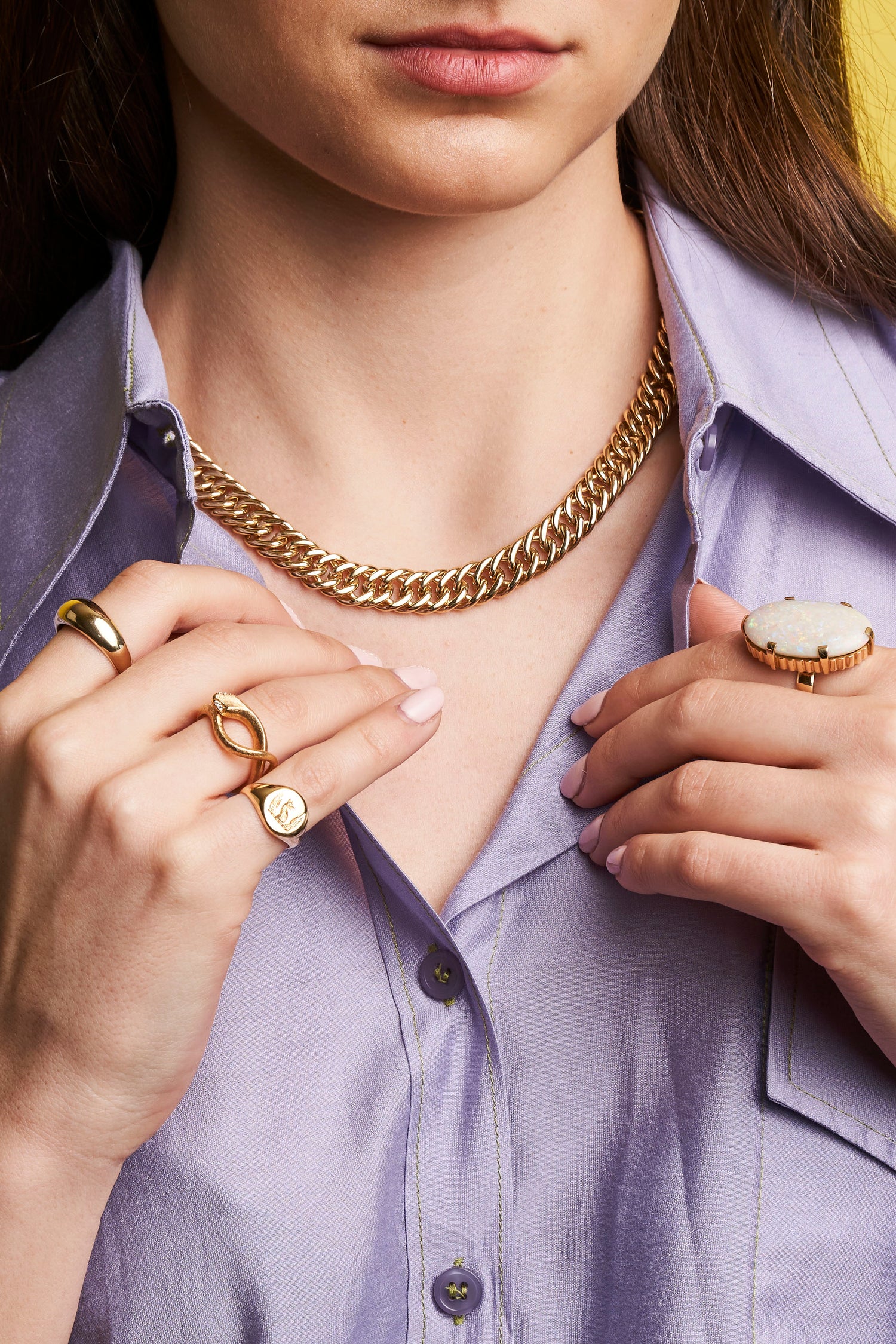 close up of woman wearing gold chain and rings with a purple shirt 
