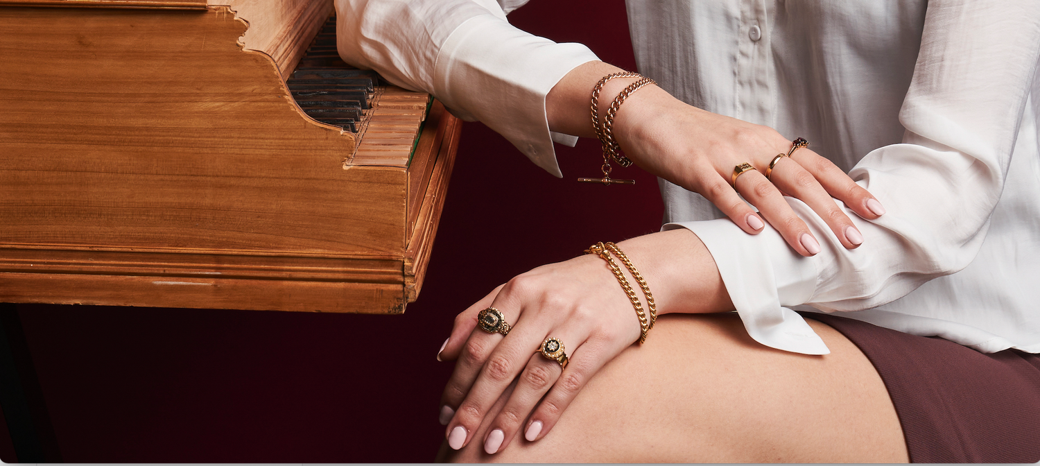 close up of woman sitting on piano stool wearing rings and bracelets